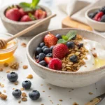 A yogurt bowl with granola, fresh berries, and honey, served in a rustic bowl on a wooden table.